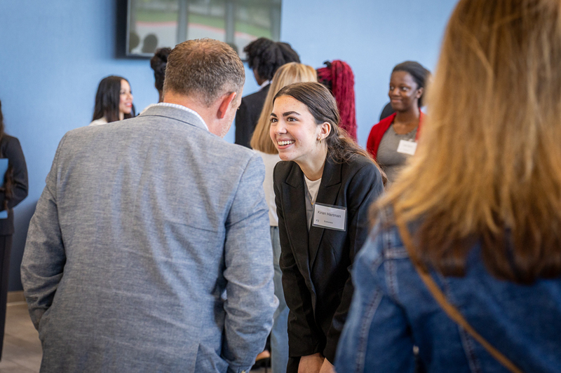 female student smiling at man as they talk before the start of the symposium