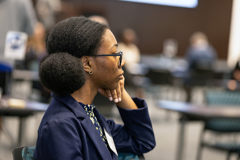 female student sits with hand against cheek waiting thoughtfully
