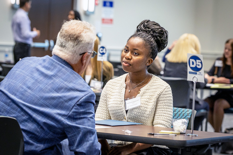female student at table talking with interviewer