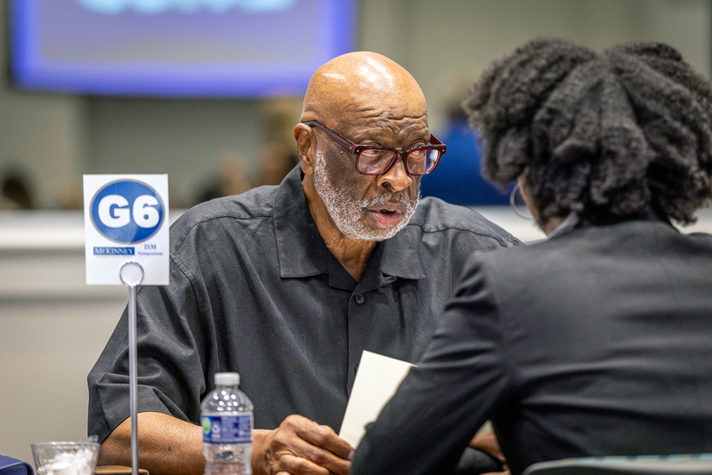 Board member Larry Jagours speaking with a female student at table during interviews