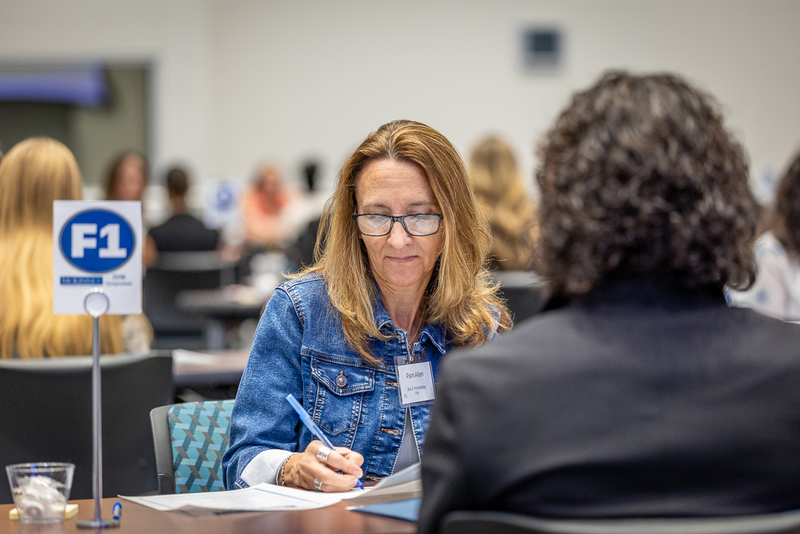 female interviewer makes notes while student is speaking