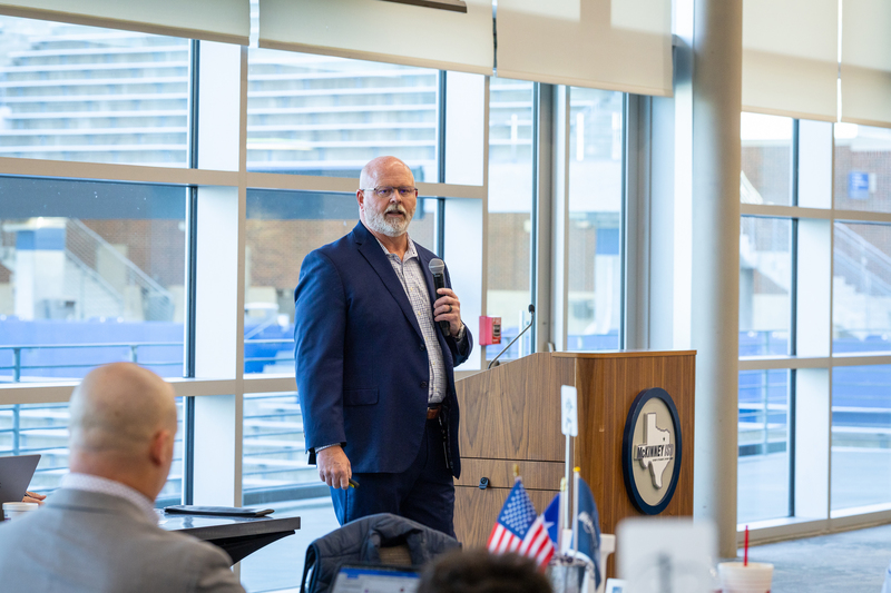Pratt in front of room with microphone speaking