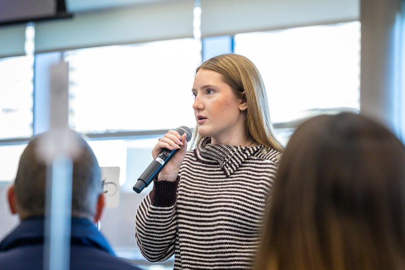 high school girl standing with microphone giving feedback during discussion