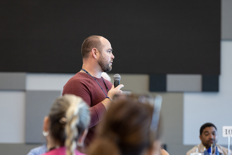 man standing with microphone giving feedback to the group during discussion