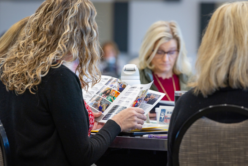woman at table looking through the MISD scorecard booklet