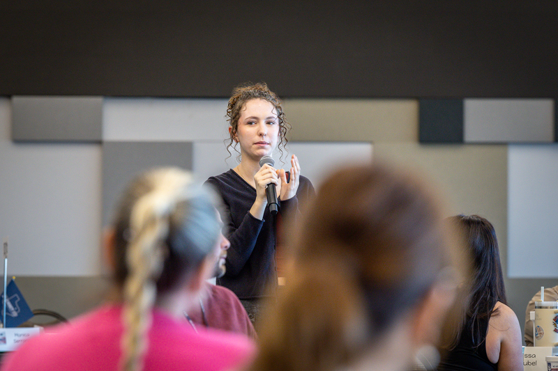 female high school student standing with microphone giving feedback during discussion