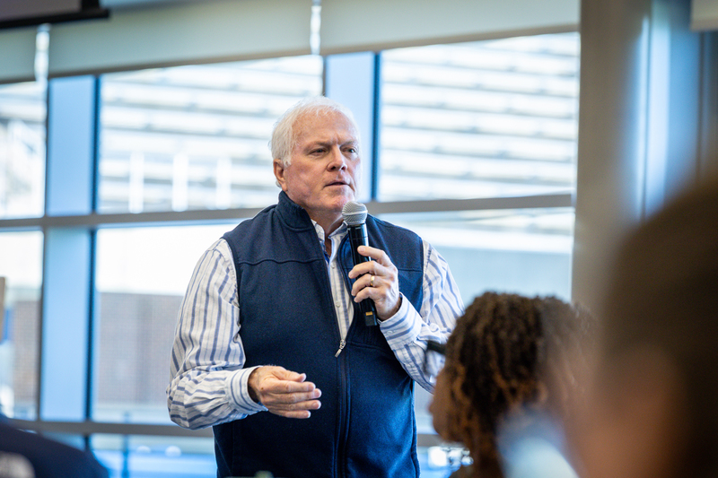 man with microphone at front of the room leading the discussion