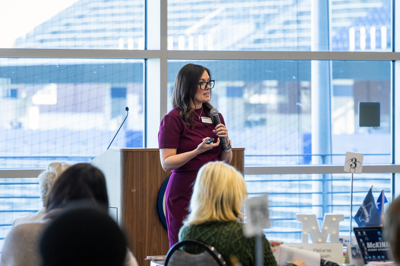 Jenny McGowan with microphone at front of the room during presentation