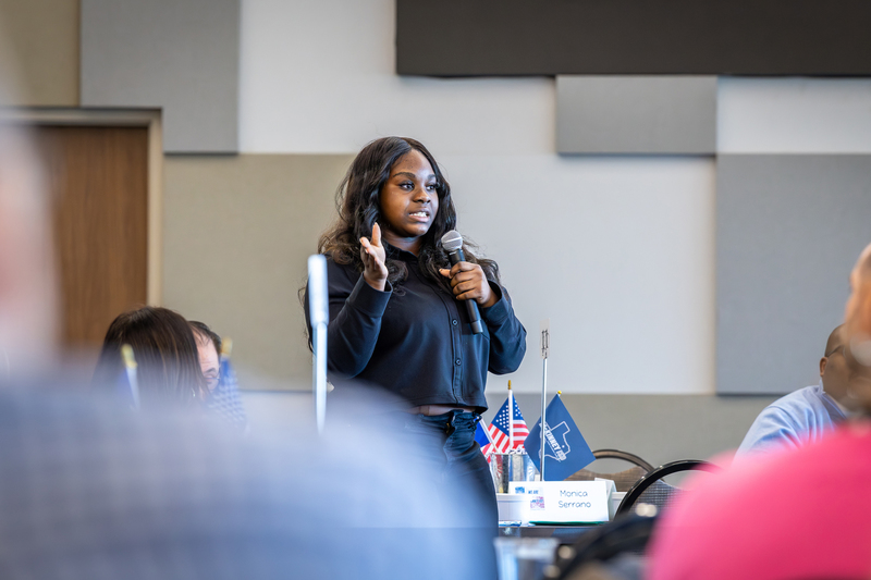 female african american high school student standing with microphone and giving feedback to the group
