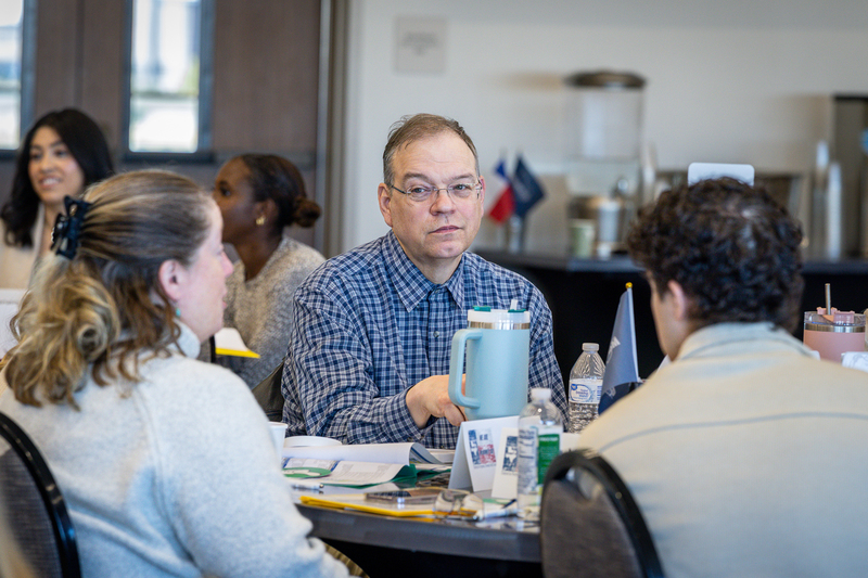 man at table listening as woman at table is speaking during discussion time