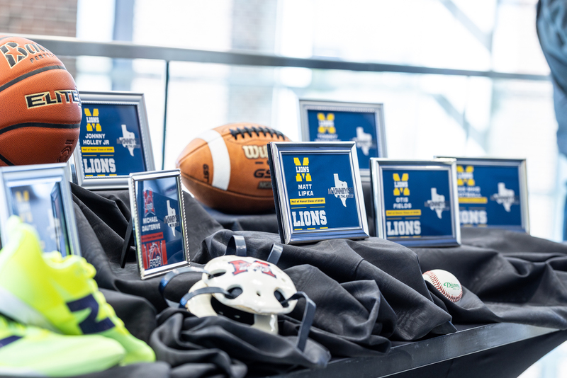 display with sports memorabilia and framed graphics with the honorees names on a table in the foyer
