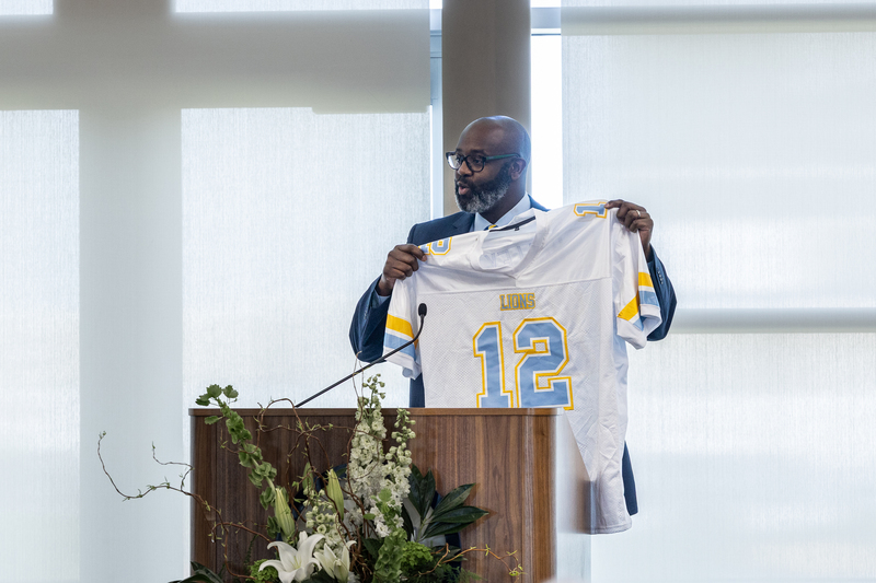 Johnny Holley Jr onstage holding up a football jersey with number 12 on it