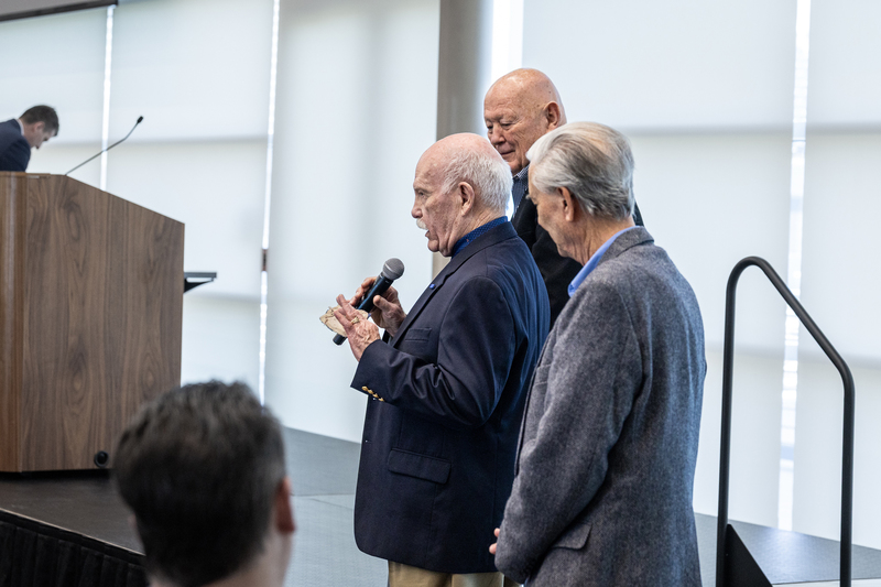 members of the 1958 football team with microphone speaking