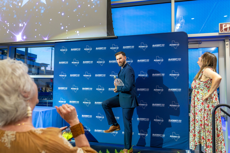 Mannis posing for photo with award like a football