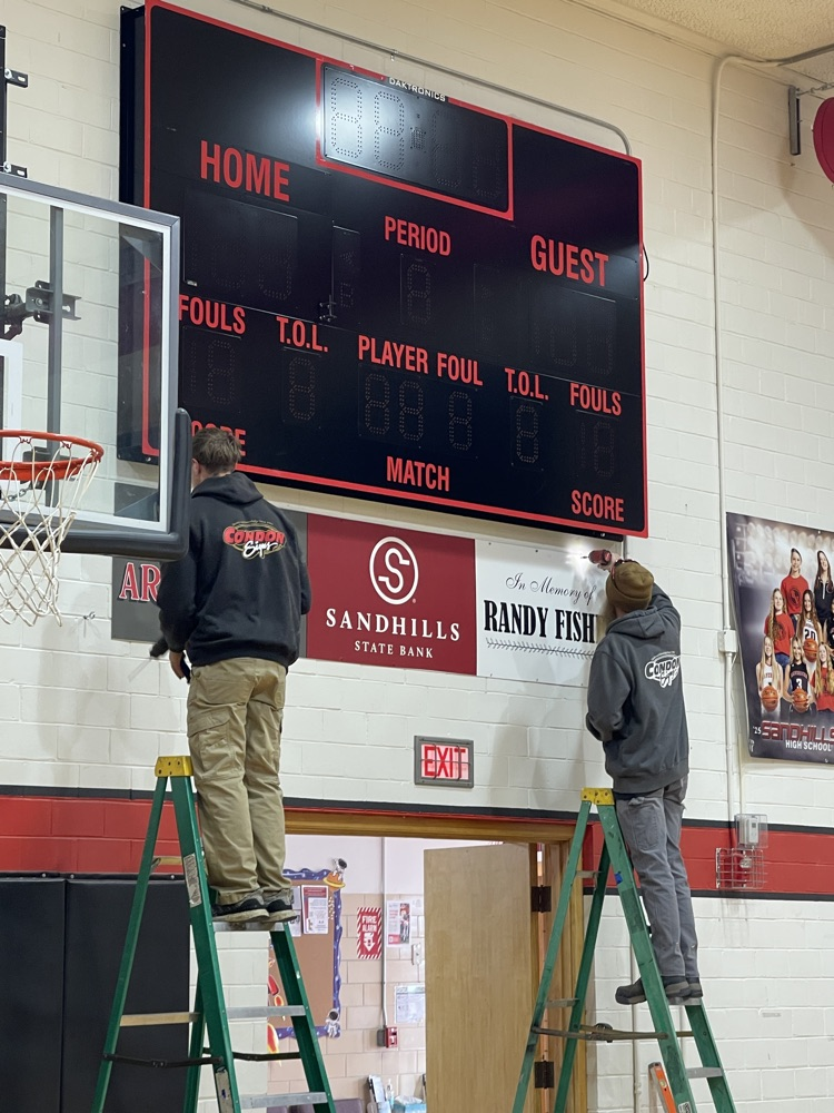 Installing signs under scoreboard .