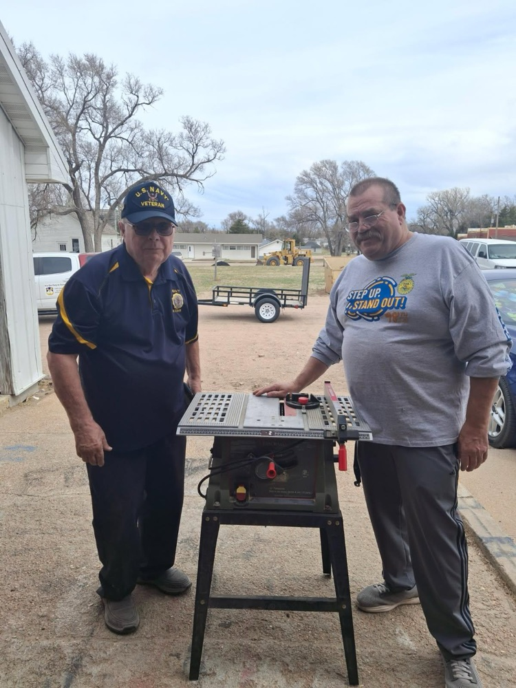 Mr. Olson and Mr. Simmons by the donated table saw .