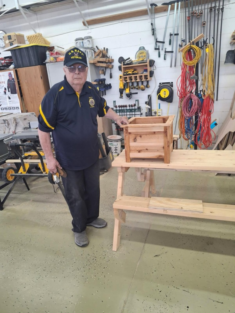 Mr. Olson by a planter made in woods.