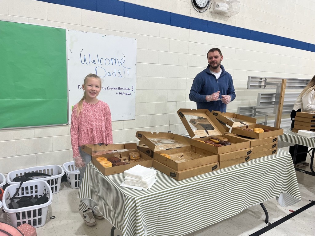students and dads having donuts for donuts with dad 
