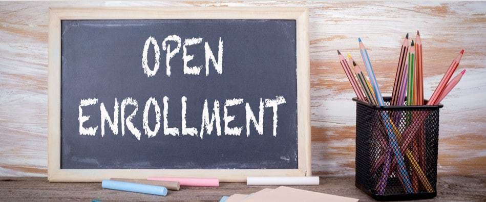 Open Enrollment Sign written in chalk, along side a jar of colored pencils. 
