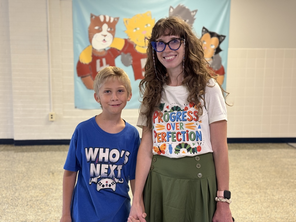 A student and his mom standing in front of a hand painted wildcat poster.