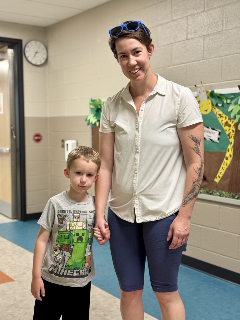 A young boy in a school hallway with a parent