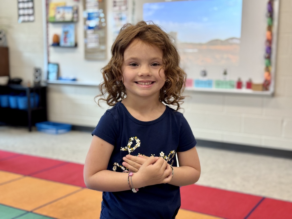 A young girl smiling in a classroom