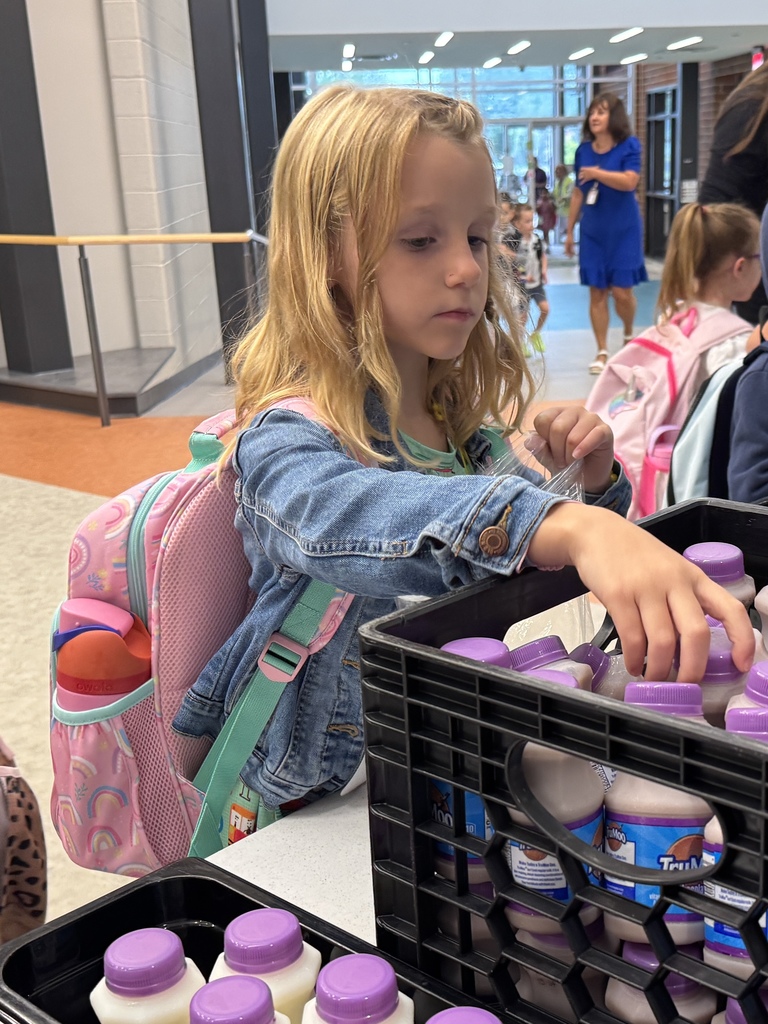 Kindergarten student picking up a bottle of milk for breakfast