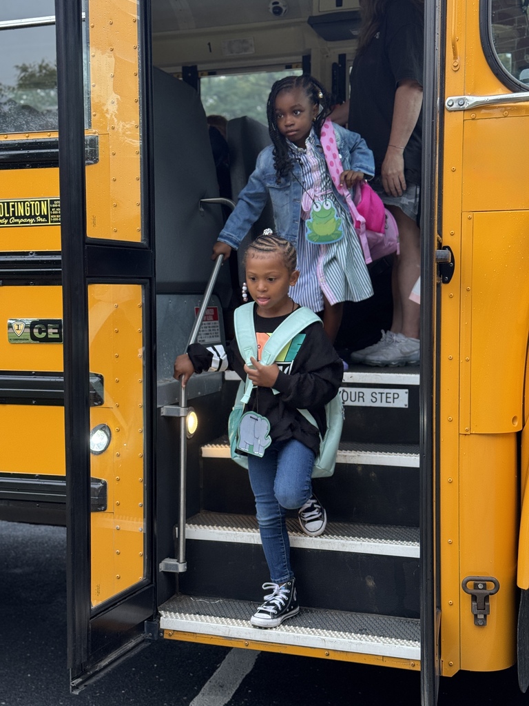 Two young students stepping off of a yellow school bus on the first day of school