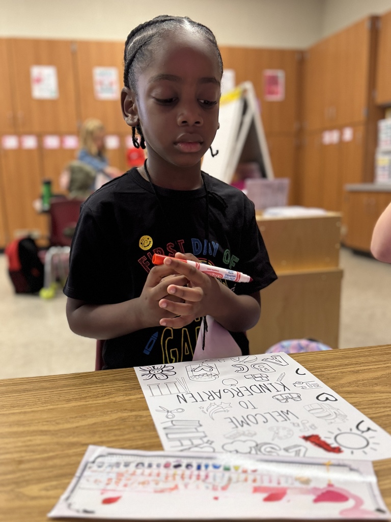 Young boy coloring a "Welcome to Kindergarten" poster
