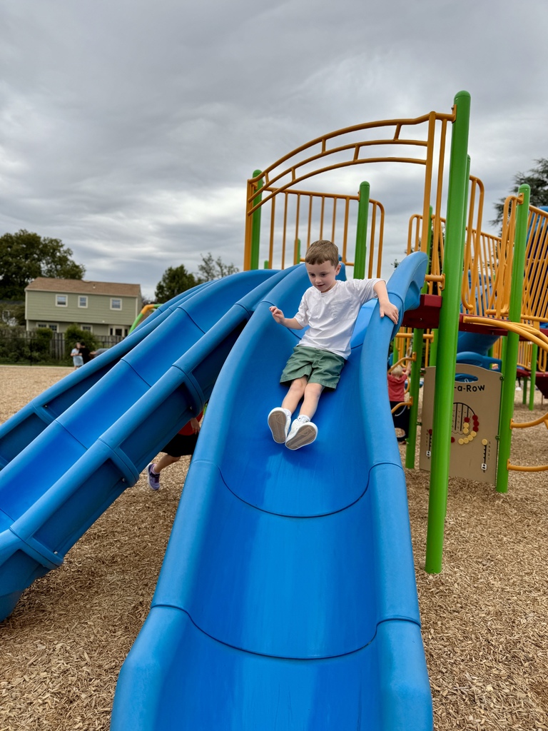 Young boy heading down a blue slide
