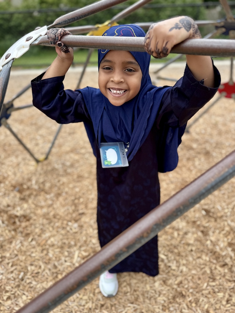 Young girl standing in between a set of monkey bars