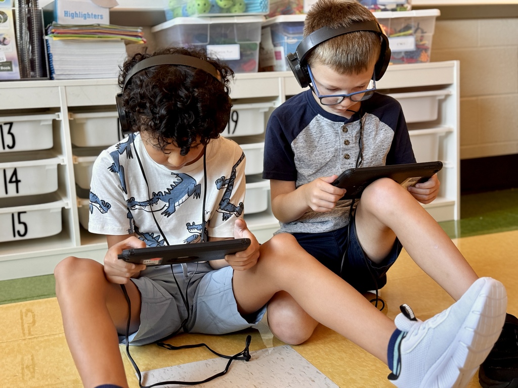 Two students sitting with ipads and headphones