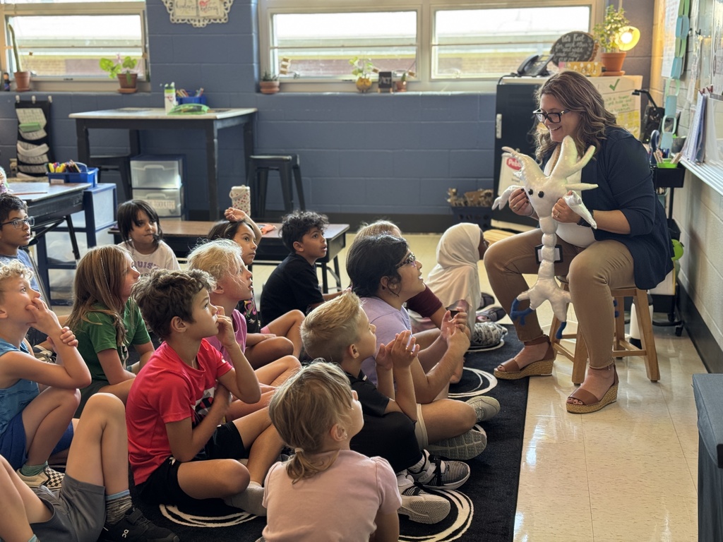 Students sitting on the floor to meet sparky, a stuffed animal