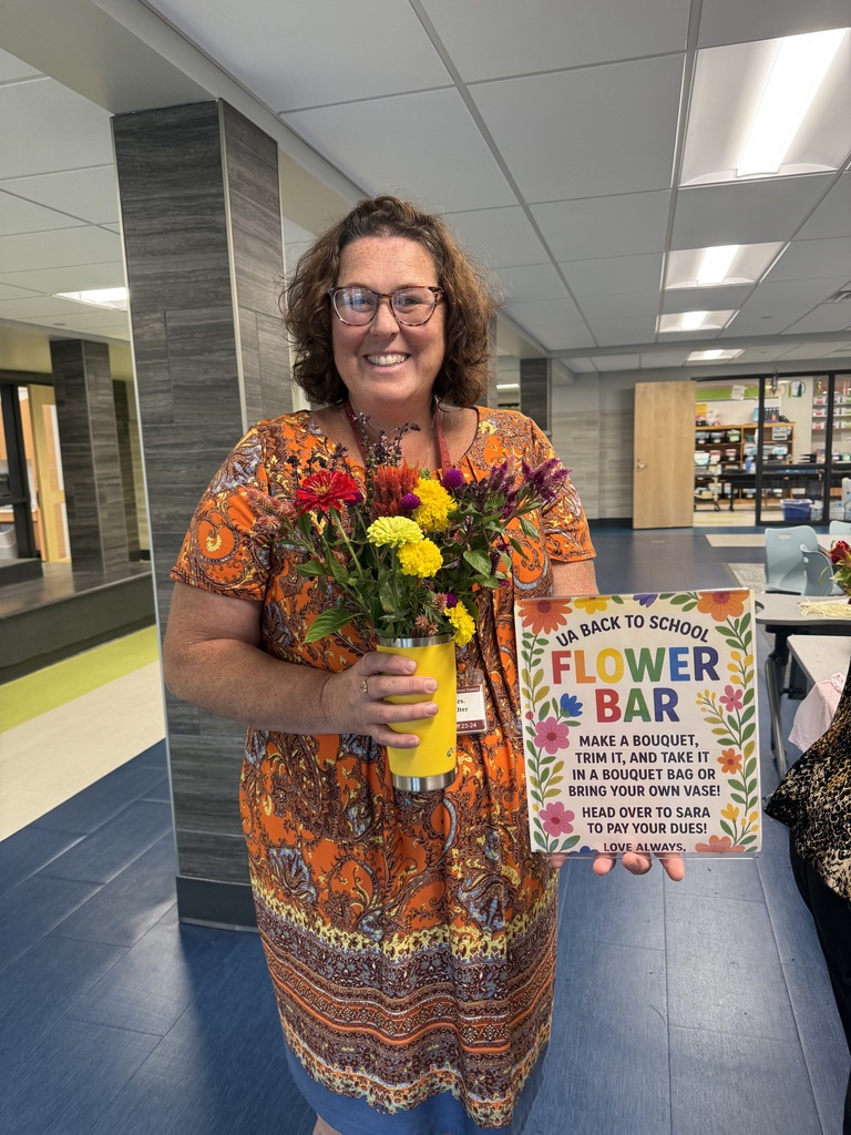 A staff member holding a handmade bouquet of colorful flowers