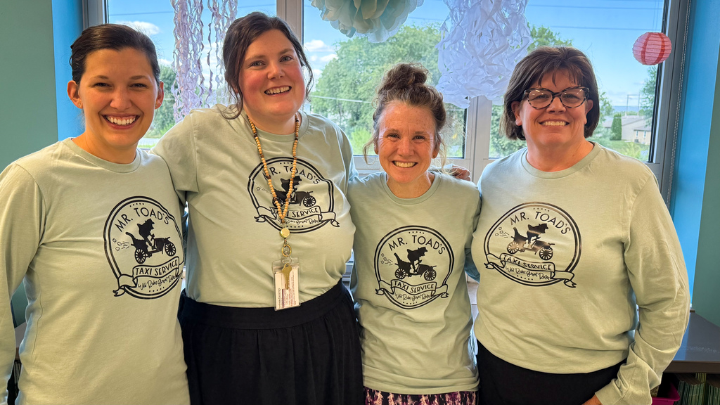 Four teachers standing together and wearing Mr. Toad's Taxi Service shirts