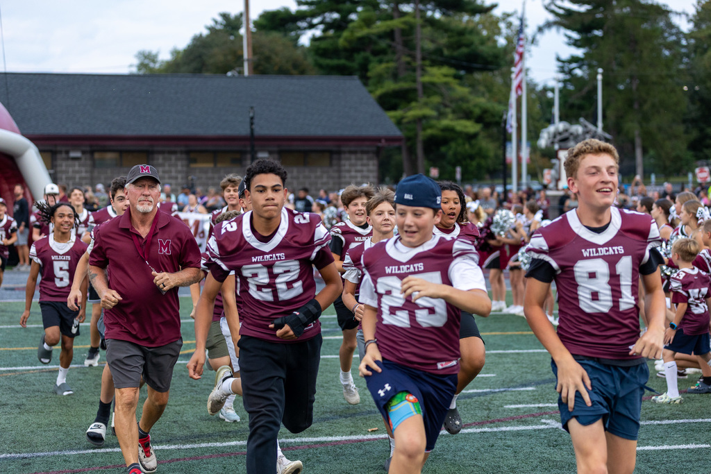 youth football players running onto the field