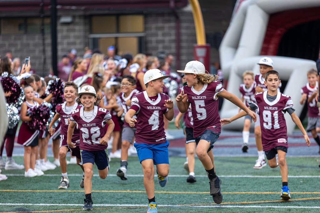 youth football players running onto the field