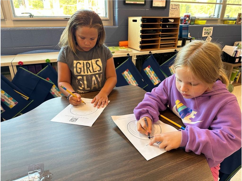 Students at a table designing dots in art class.