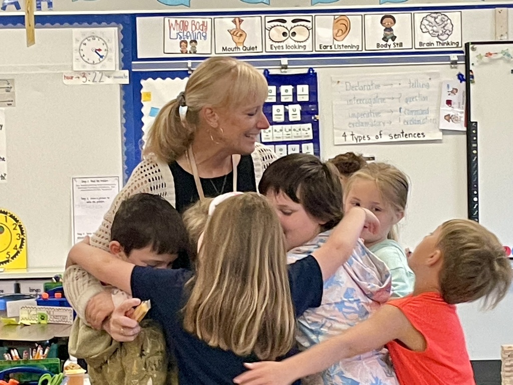 Students gathering around and hugging a teacher. So many smiles!