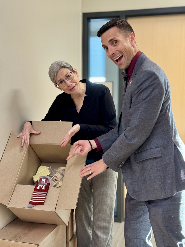 A man and woman stand behind and beside a pile of boxes.
