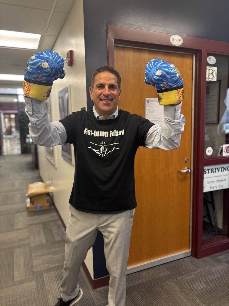 A principal holding up oversized "fist" gloves for Fist Bump Friday.