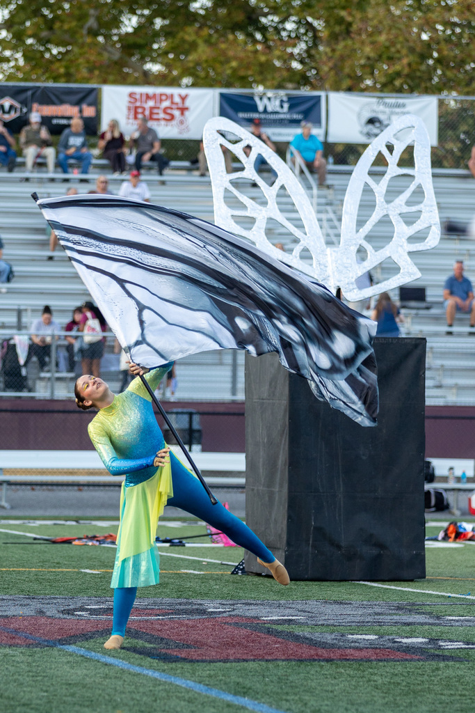 A member of the color guard wearing a colorful costume and carrying a flag. 