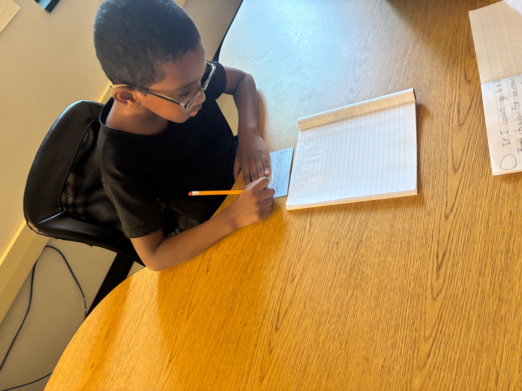 Student sitting at a desk writing on a notecard
