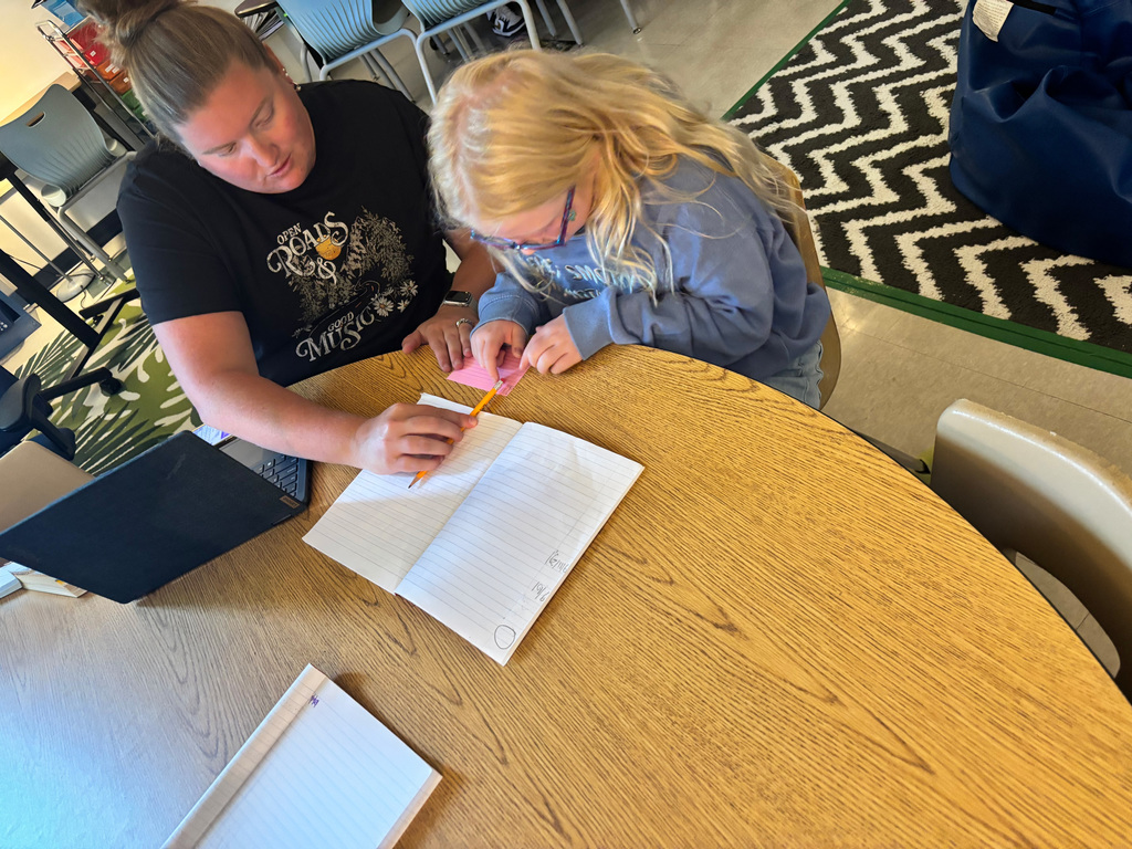 A teacher helping a student write on a notecard