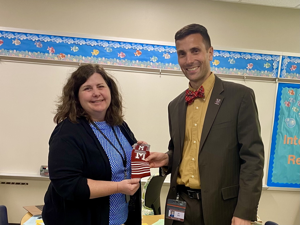 A superintendent presents a staff member with a pair of branded socks