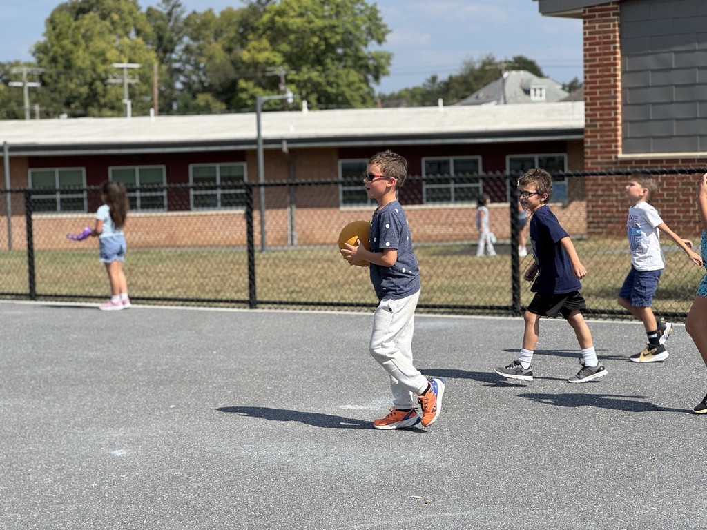 three young boys play kickball at recess