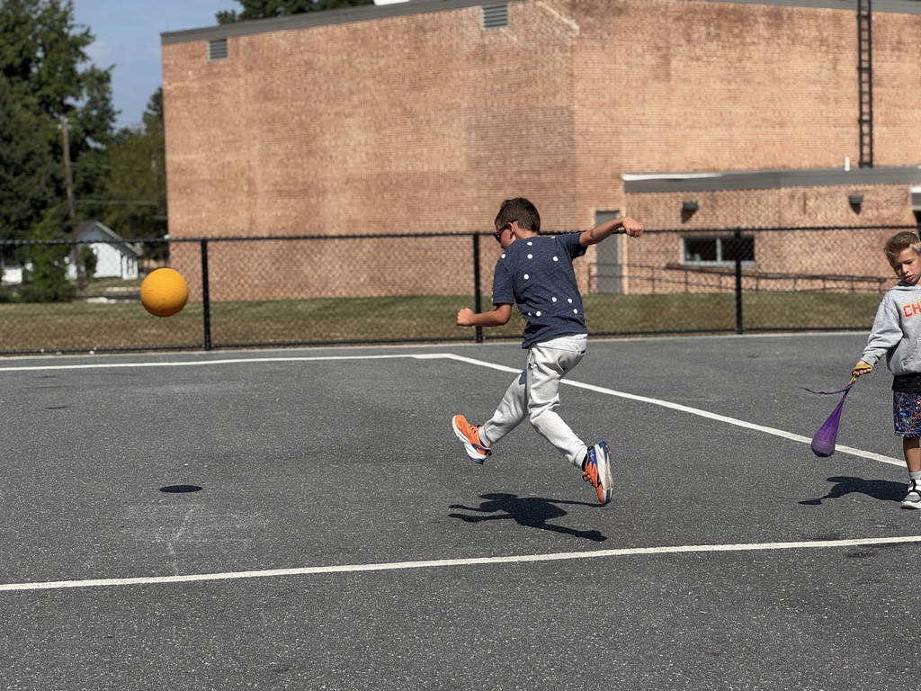 A young boy kids a ball at recess.