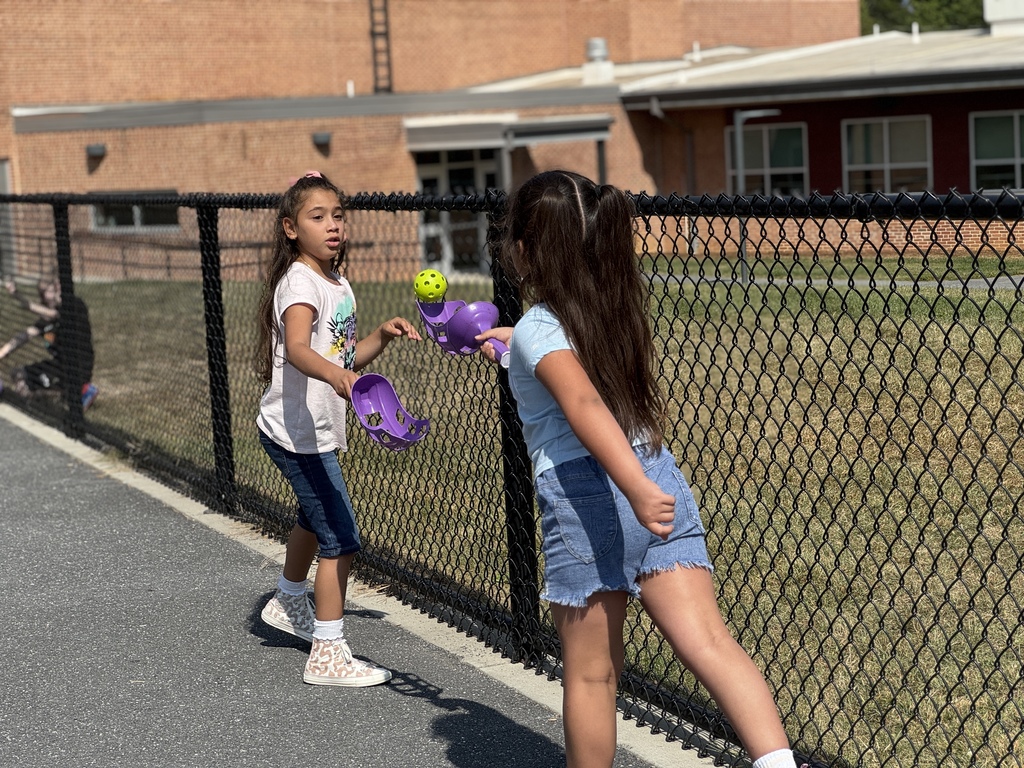Two girls tossing and catching a wiffle ball at recess