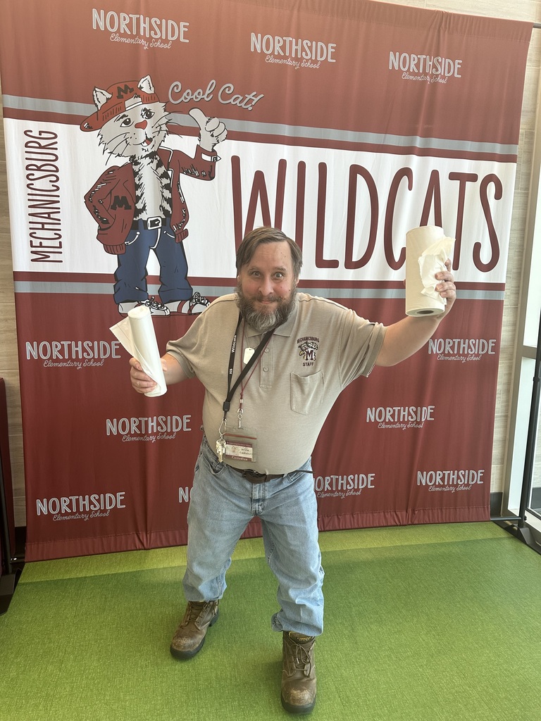 Man standing in front of a sign with paper towels. He's being funny.