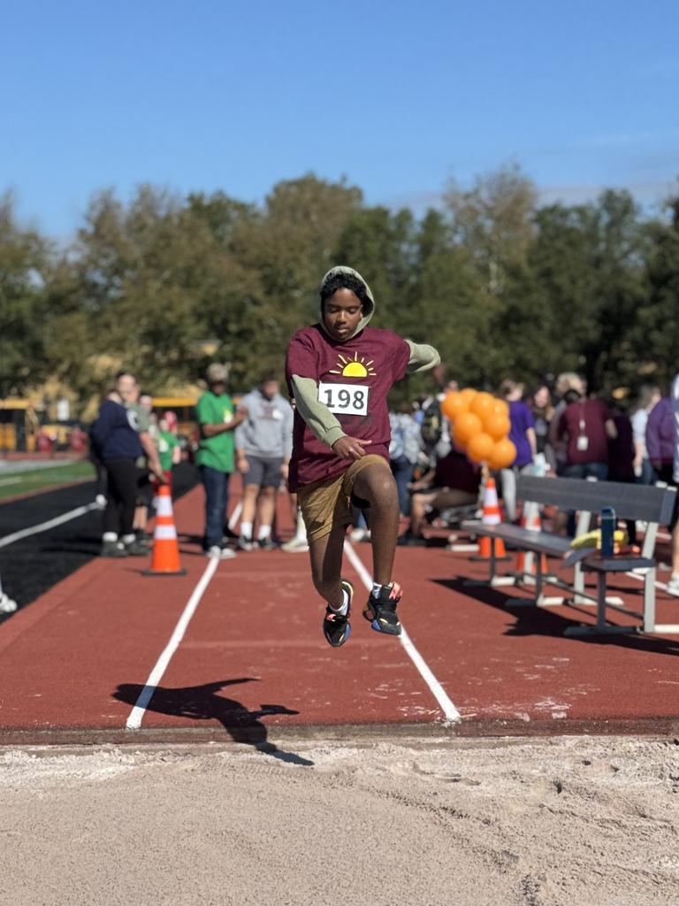A special olympian competing in the long jump. He's mid air.